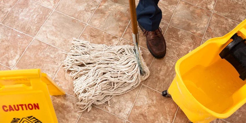 Mop, wet-floor sign and bucket on a tile retail floor